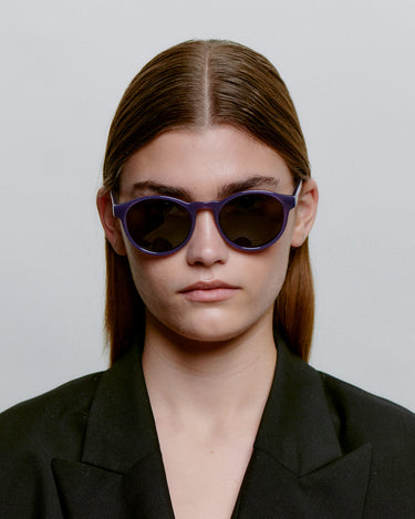 Runde lilla A.Kjærbede solbriller med mørk linse foran på kvindemodel