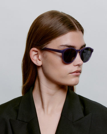 Runde lilla A.Kjærbede solbriller med mørk linse fra siden på kvindemodel 