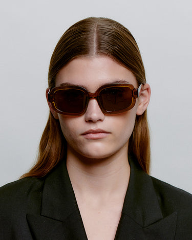 Store brune firkantet A.Kjærbede solbriller med mørk glas - foran på kvindemodel